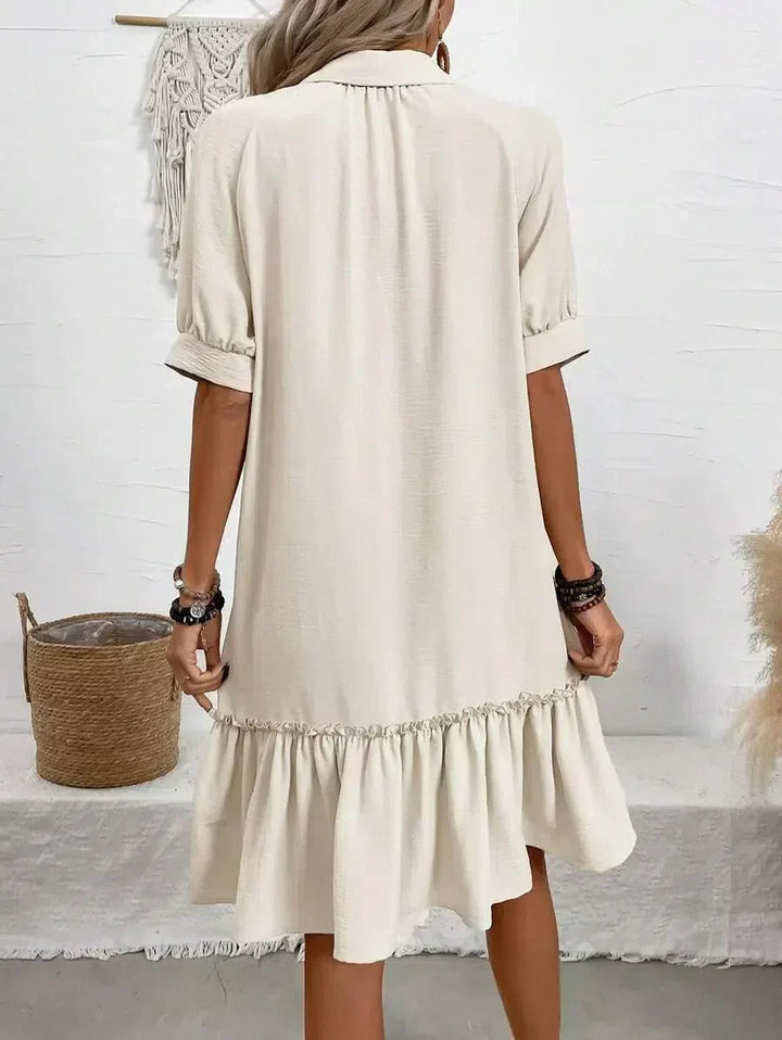 Rear view of cream shirt dress showing ruffled hemline and rolled sleeves