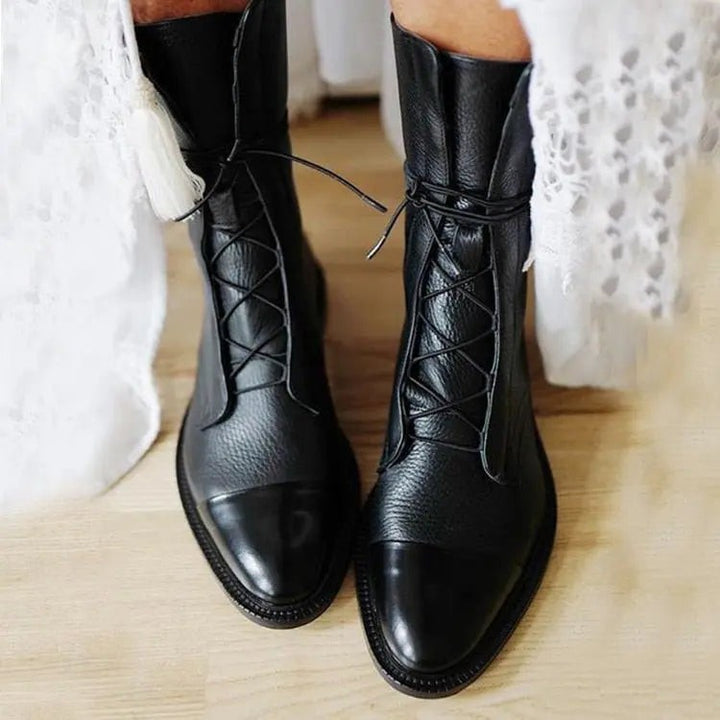 Black leather lace-up ankle boots with glossy toe cap, worn with lace hem dress