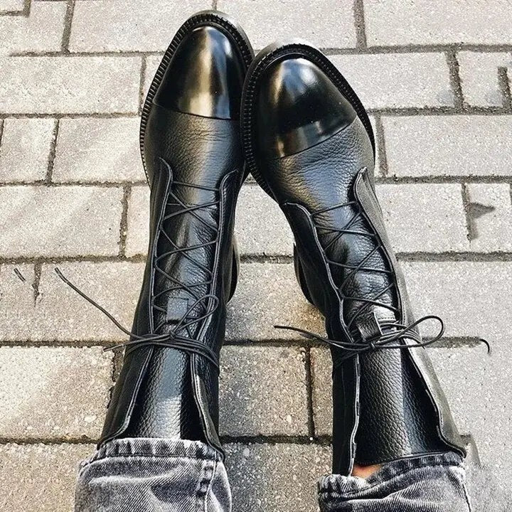 Black leather lace-up ankle boots featuring polished cap toe, styled with distressed denim
