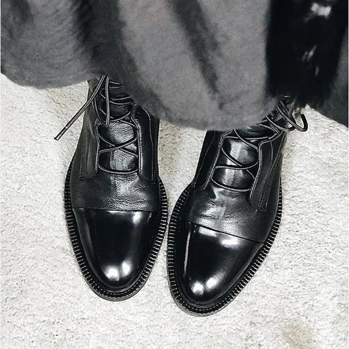 Glossy black leather ankle boots with contrast toe cap and lace-up front detail