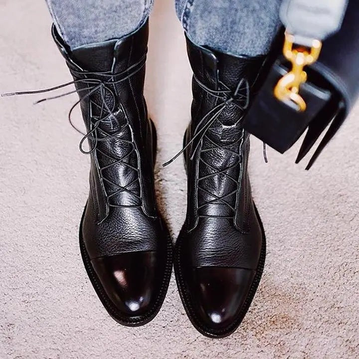 Black leather lace-up boots with shiny cap toe, paired with cropped denim jeans