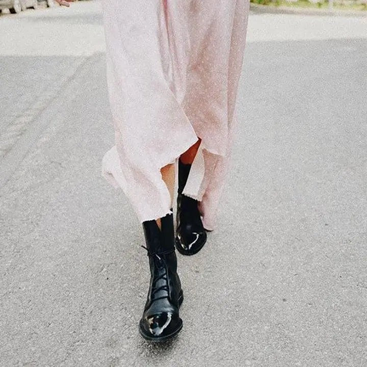 Black leather lace-up boots with glossy toe, styled walking in a pastel pink dress