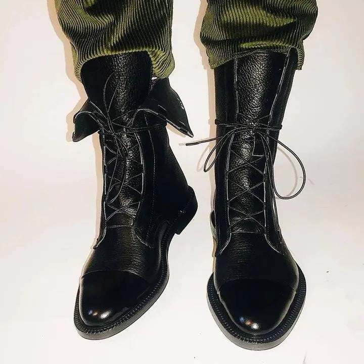 Black leather lace-up boots featuring cap toe detail, worn with green corduroy trousers