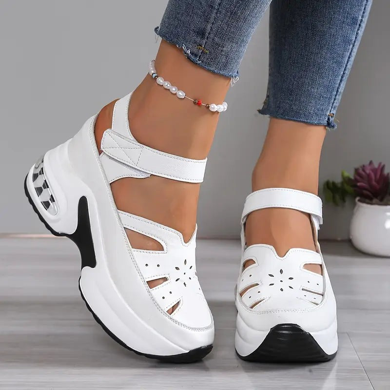 White wedge sandals featuring floral cut-outs and touch-strap ankle closure