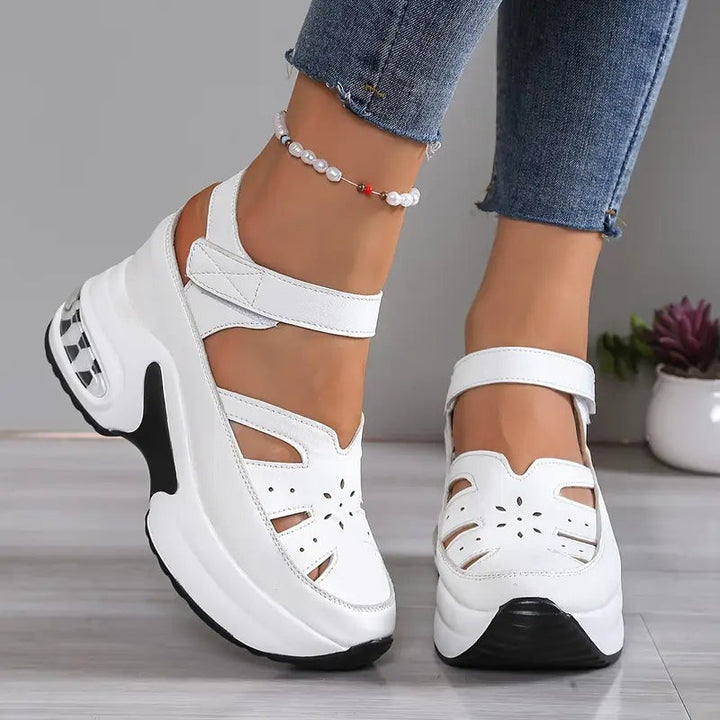 White wedge sandals featuring floral cut-outs and touch-strap ankle closure