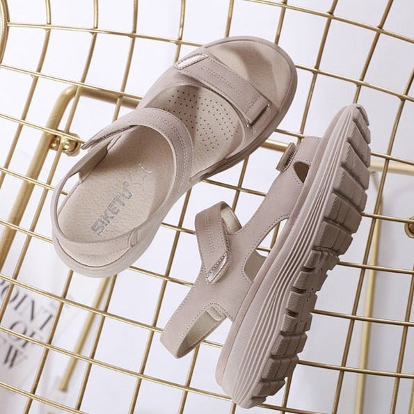 Pair of beige Velcro-strap sandals displayed on decorative wire basket