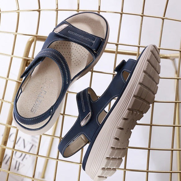 Navy Velcro sandals with beige sole displayed on gold wire rack