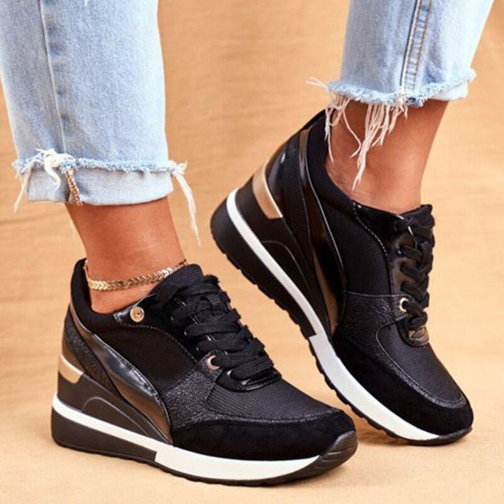 Side view of black platform sneakers with bronze metallic accents