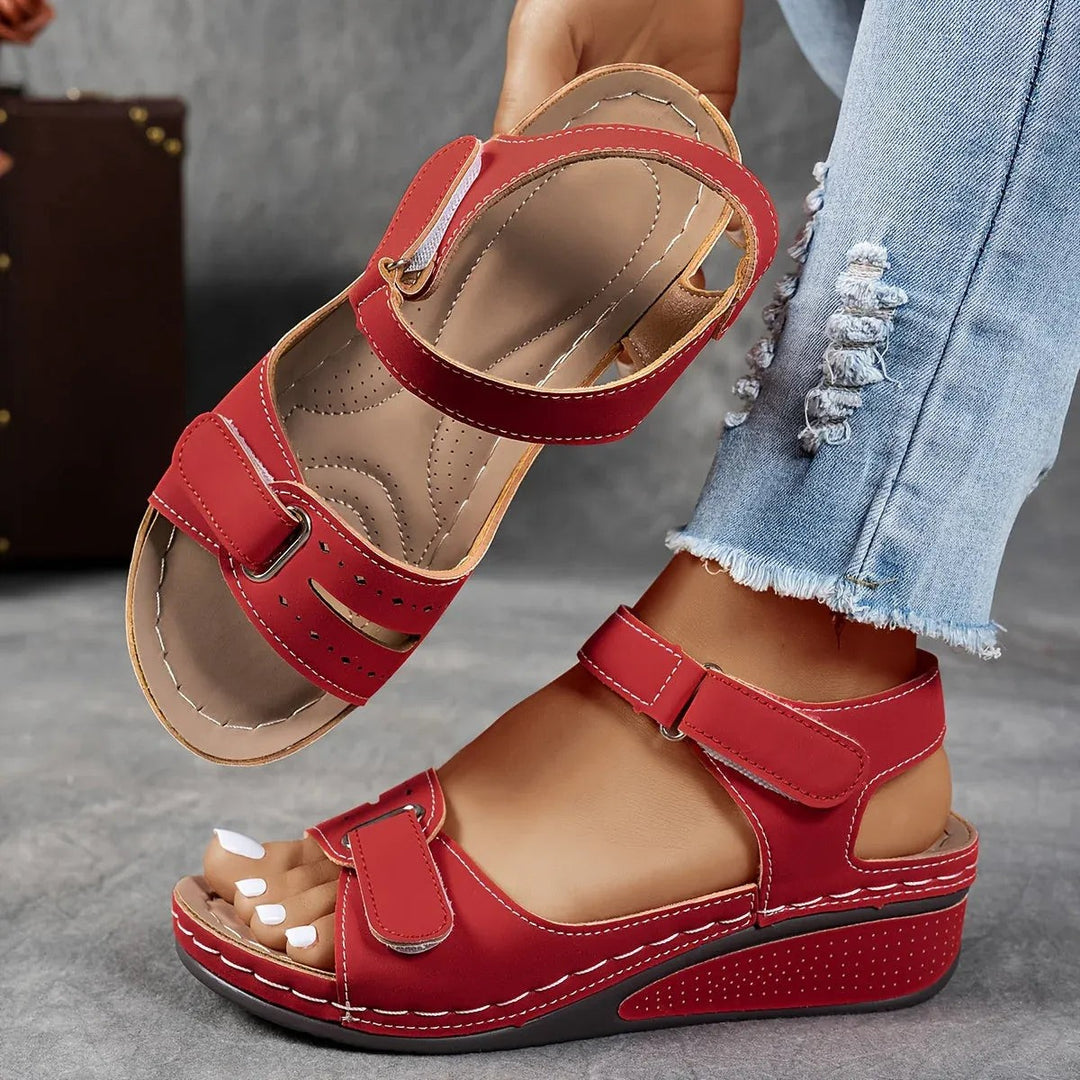 Red orthopedic wedge sandals worn on feet, showing cushioned footbed detail