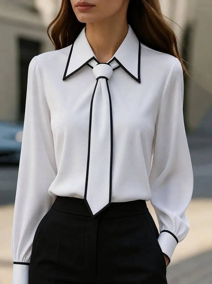 White contrast-trim blouse with tie-neck detail and pointed collar, styled with black skirt