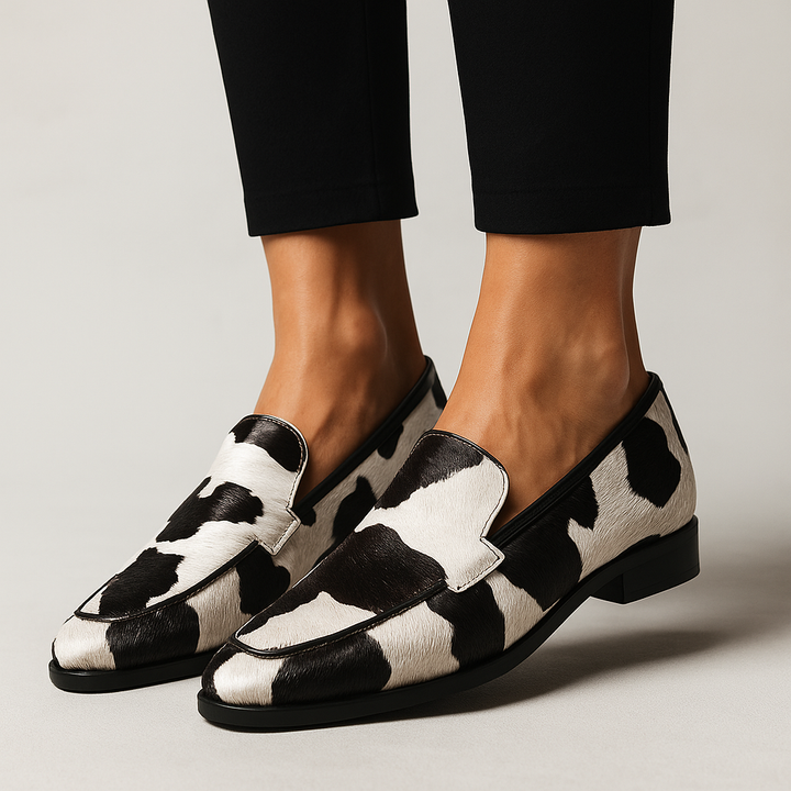Black and white cow-print loafers worn with cropped tailored trousers
