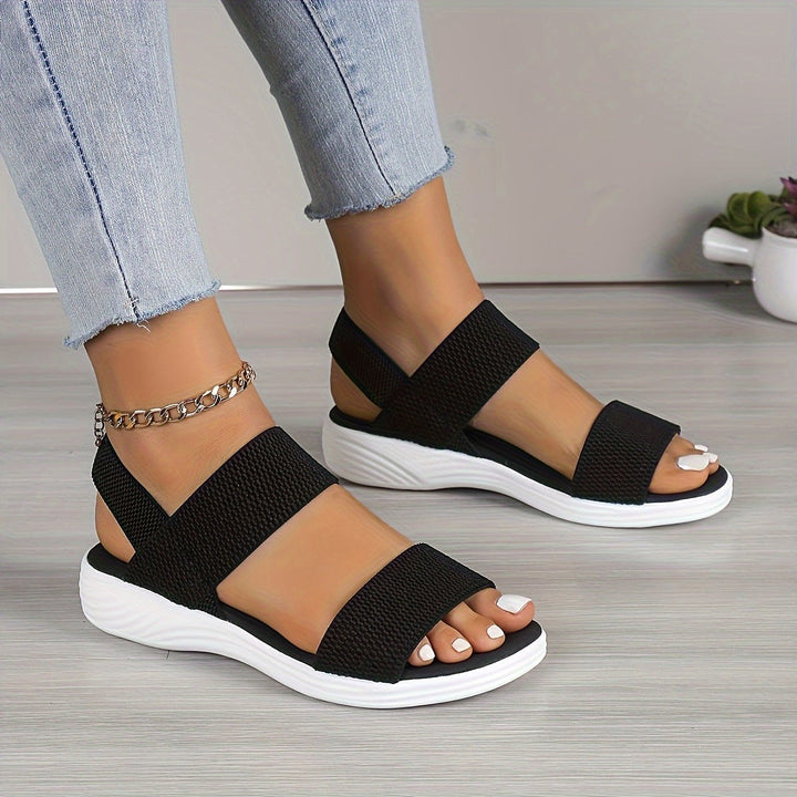 Black open-toe sandals with ankle strap and cushioned white wedge sole
