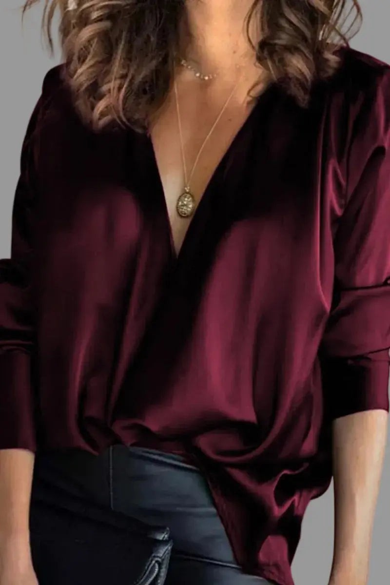 Burgundy satin blouse featuring draped V-neckline and long sleeves