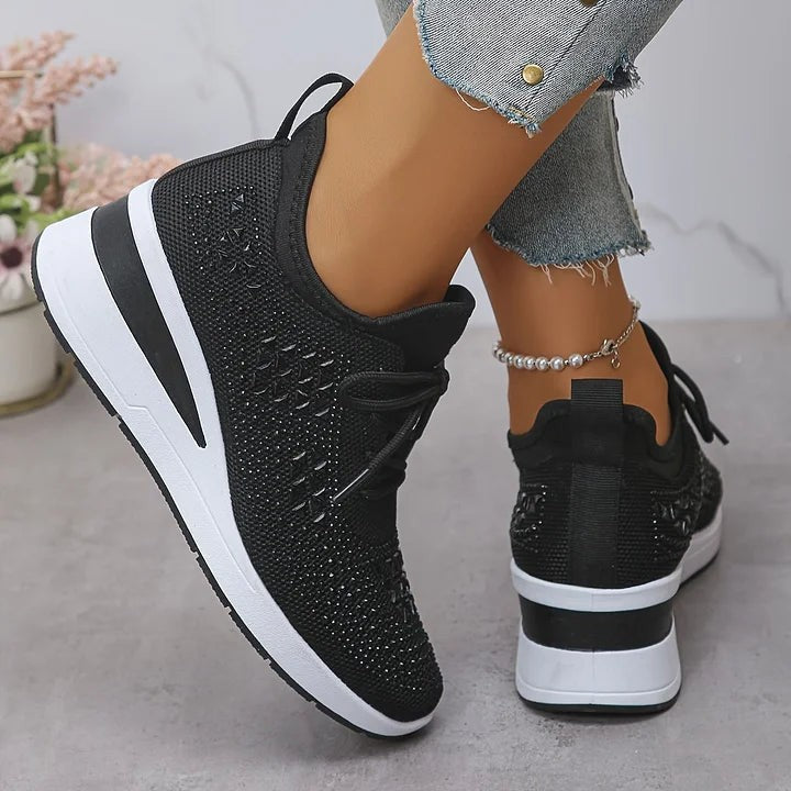Black knitted wedge trainers viewed from behind with striped sole detail