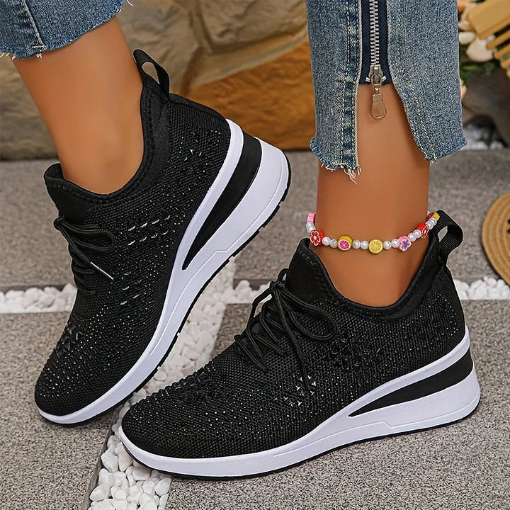 Black knitted trainers with sparkling star detailing worn outdoors