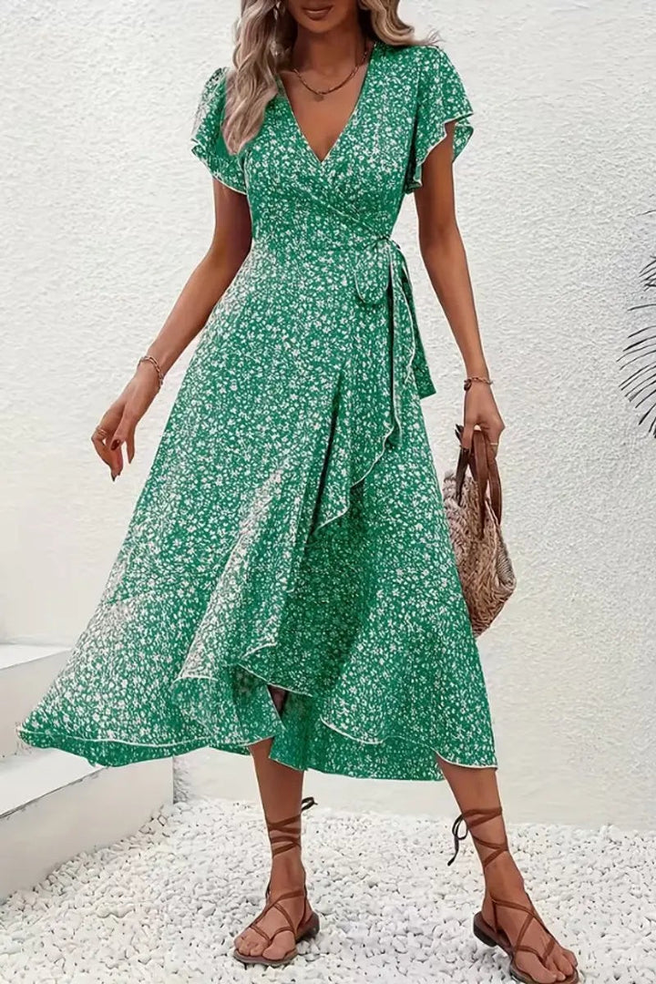 Green ditsy floral wrap dress worn with straw handbag and strappy sandals