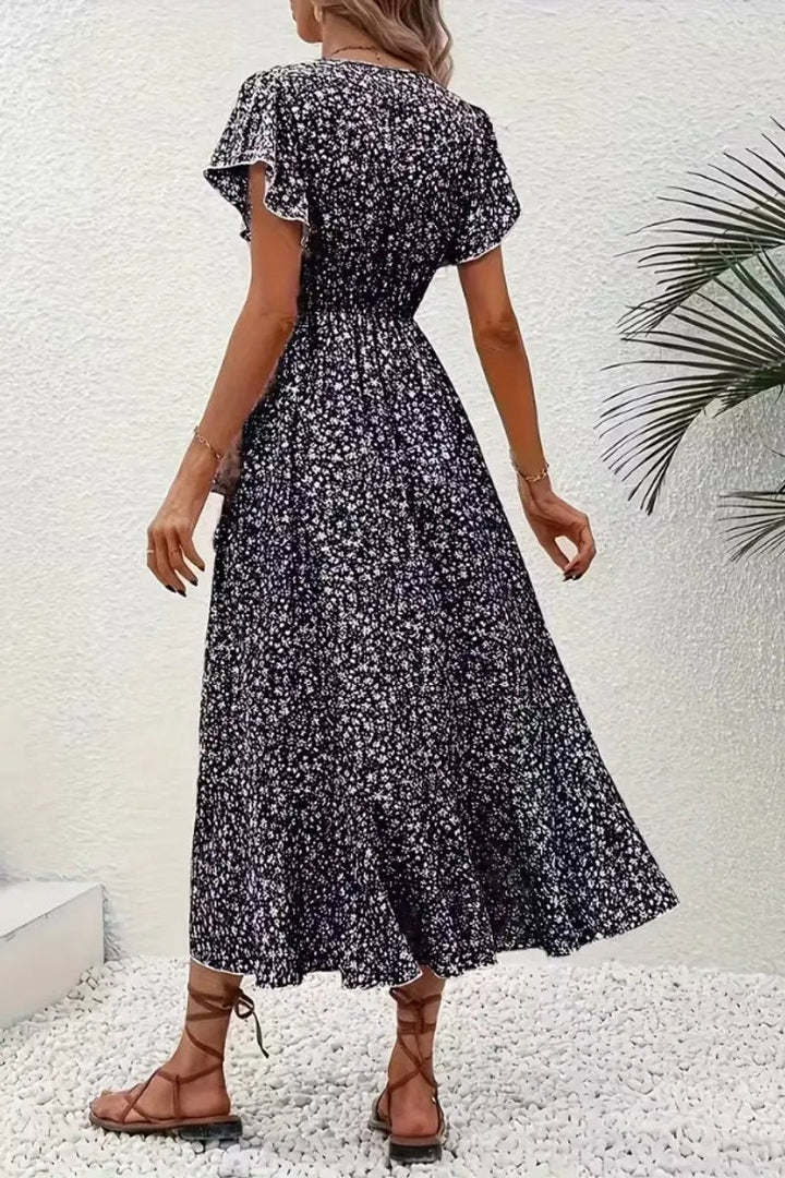 Rear view of black floral wrap dress showing fitted waist and flowing skirt
