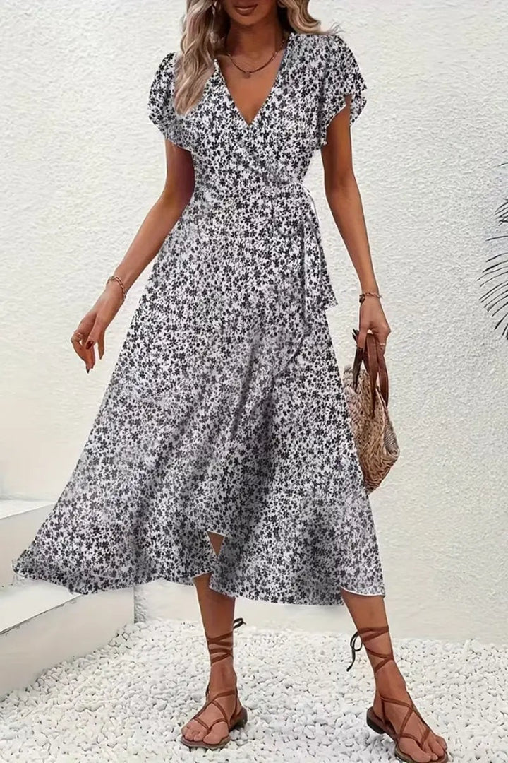 Black and white floral wrap dress paired with woven handbag and sandals