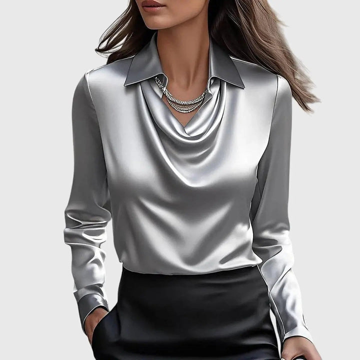 Silver satin blouse featuring draped cowl neck and long sleeves, paired with black skirt