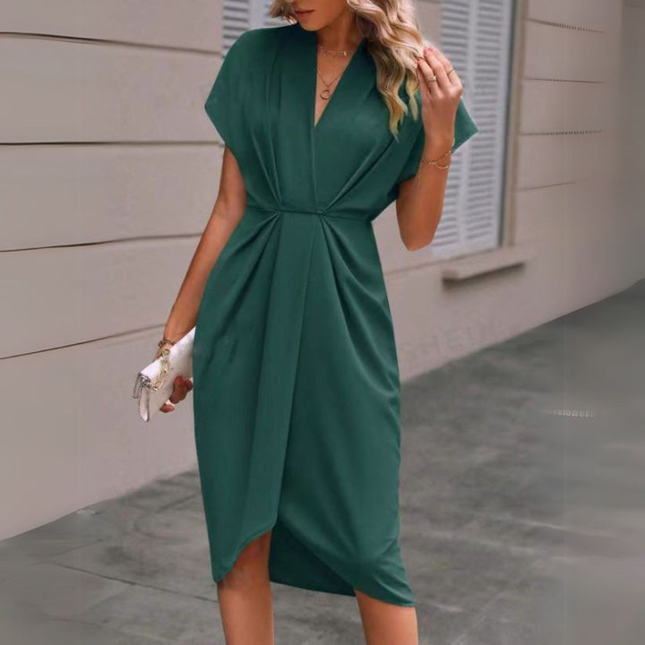 Emerald green draped midi dress with V-neckline paired with white clutch