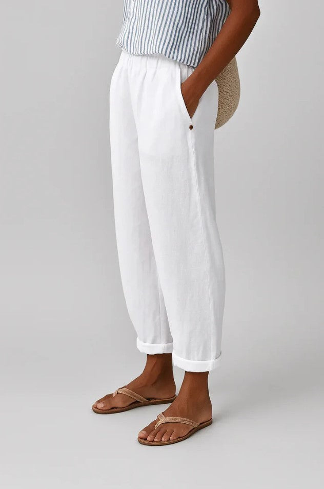 White cropped turn-up trousers styled with woven flip-flops and straw bag