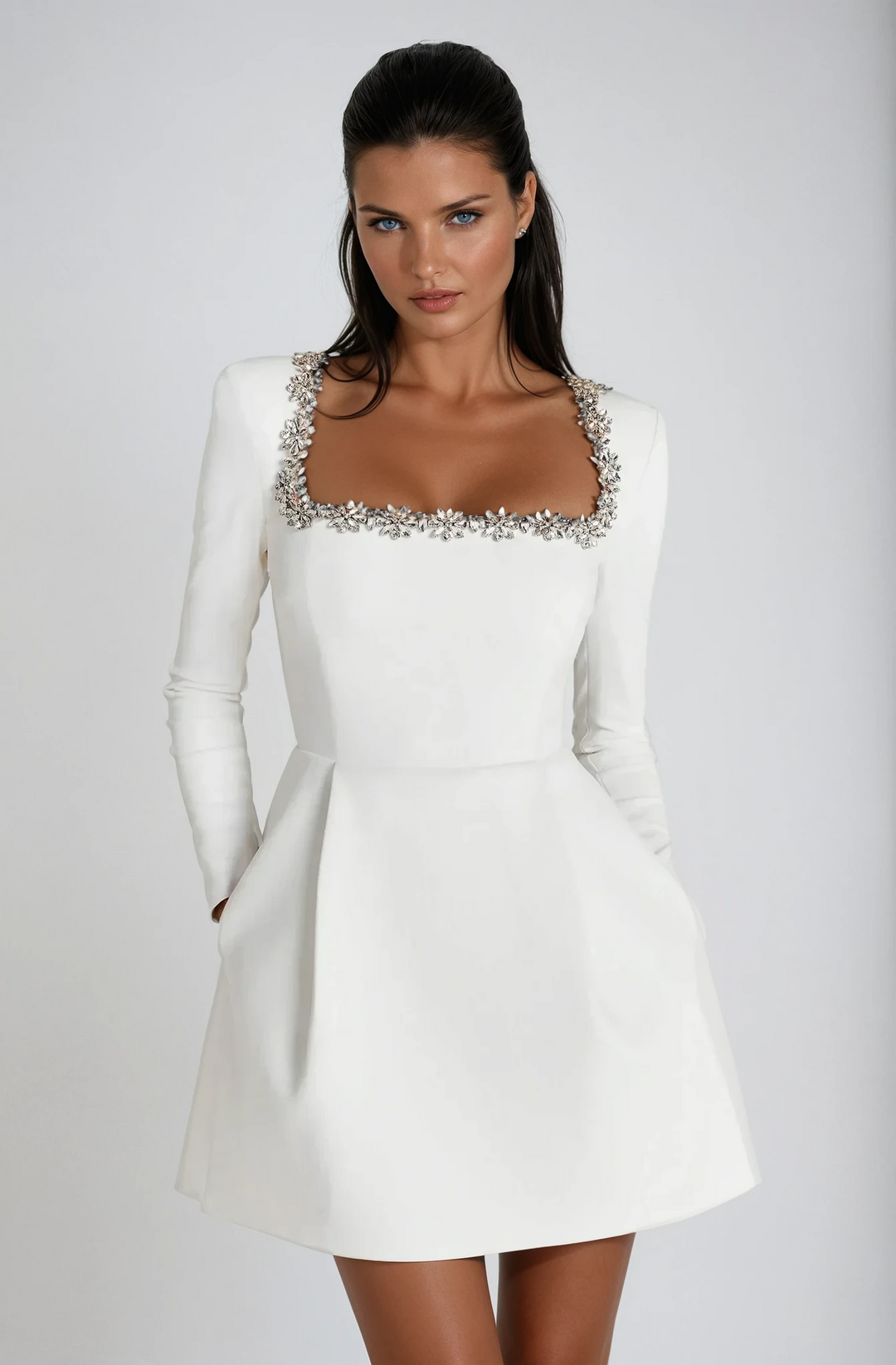 White long-sleeve mini dress showing crystal trim and flared hemline