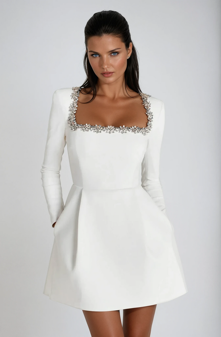 White long-sleeve mini dress showing crystal trim and flared hemline