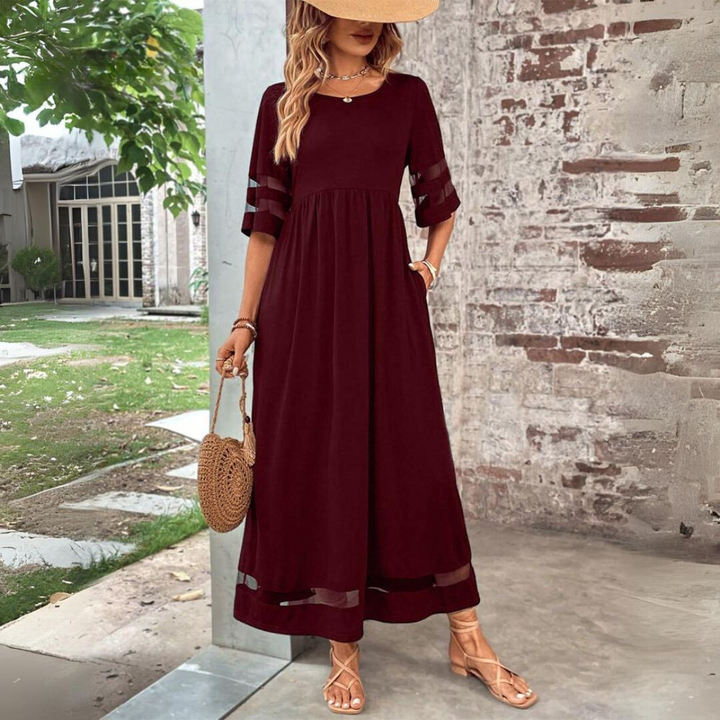 Burgundy maxi dress with mesh sleeve inserts and empire waist, paired with a straw bag