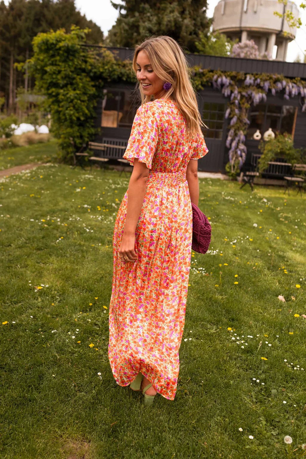 Rear view of orange floral maxi dress showing flutter sleeves and flowing skirt