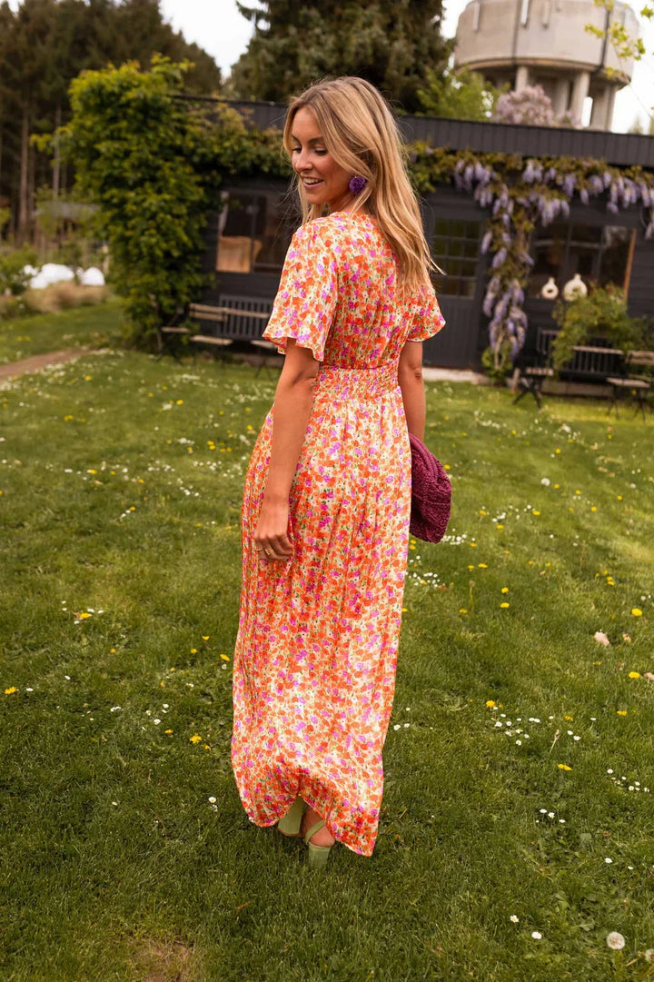 Rear view of orange floral maxi dress showing flutter sleeves and flowing skirt