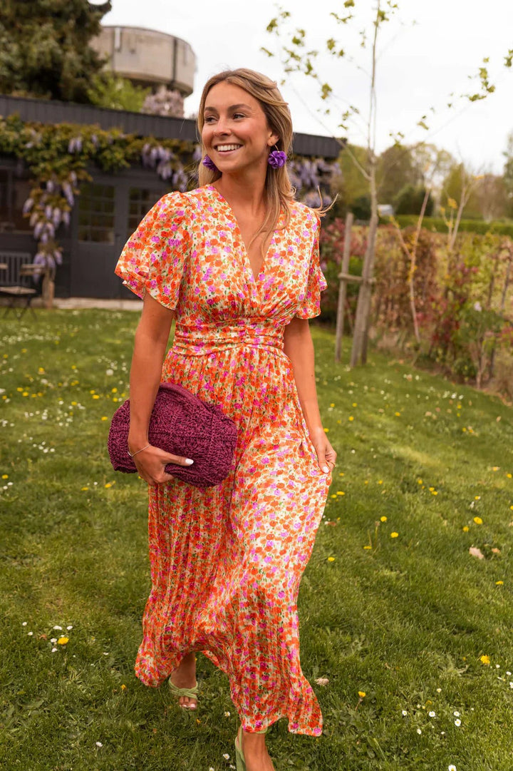 Orange floral maxi dress with V-neckline paired with a maroon crochet clutch