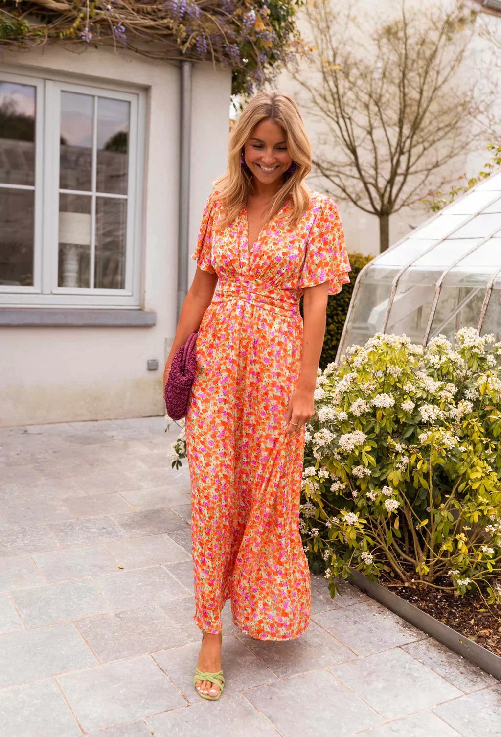 Full-length orange floral maxi dress with wrap front, styled with green heeled sandals