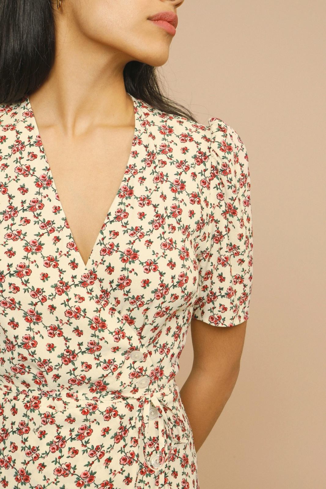 Close-up of floral wrap dress showing button front and tie belt detail