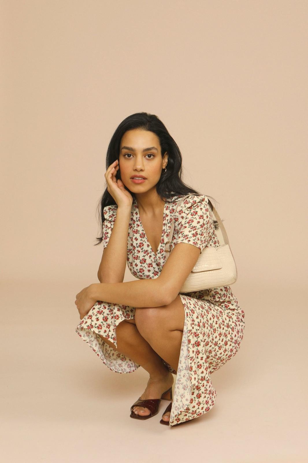 Model crouching in floral midi dress paired with croc-effect shoulder bag