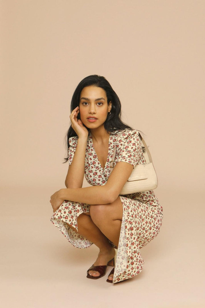 Model crouching in floral midi dress paired with croc-effect shoulder bag