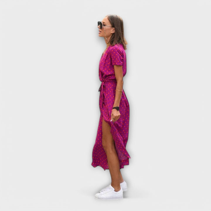 Side profile of magenta polka dot midi dress showing tie waist and split hem