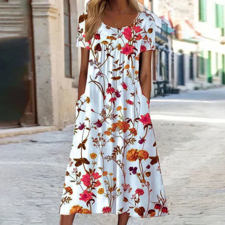 White floral maxi dress with short sleeves and wildflower print, worn on cobbled street