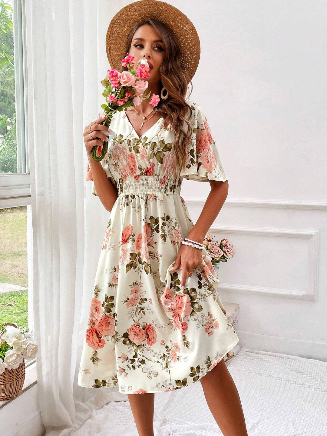 Model twirling in cream floral midi dress with flutter sleeves and full skirt