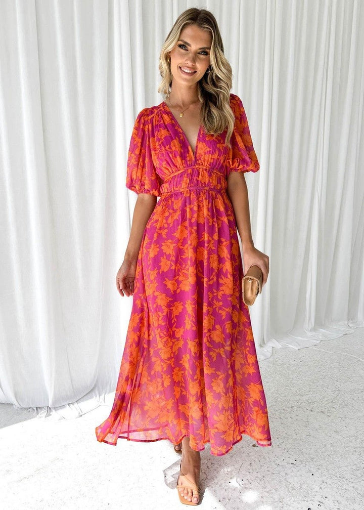 Floral V-neck midi dress paired with tan clutch and strappy heels