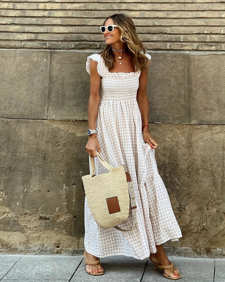 Beige gingham flutter sleeve maxi dress worn with woven tote and strappy sandals