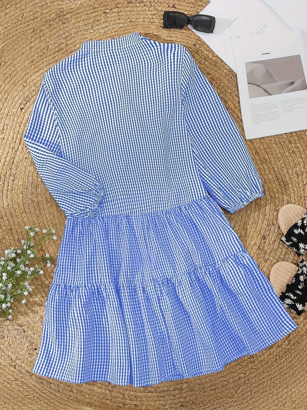 Blue gingham shirt dress laid flat displaying tiered skirt and full sleeves
