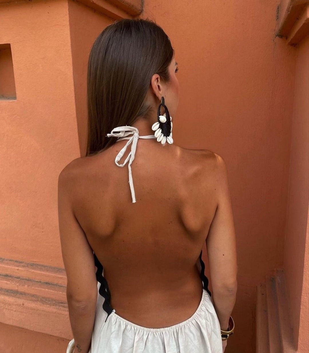 Backless white maxi dress showing halterneck tie and scalloped black edging