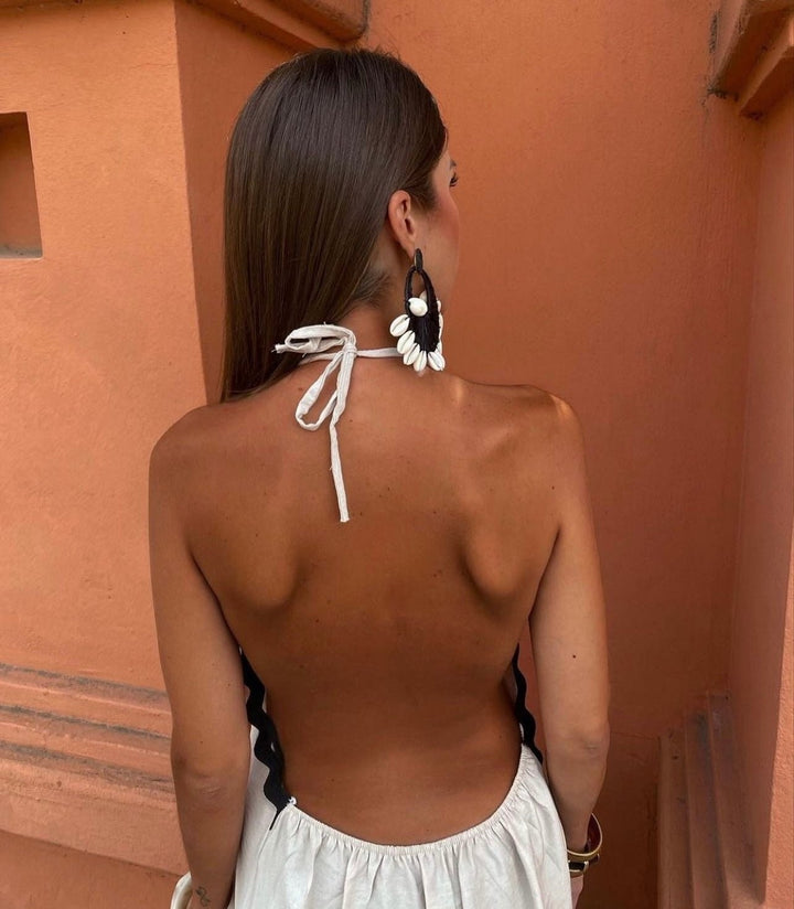 Backless white maxi dress showing halterneck tie and scalloped black edging