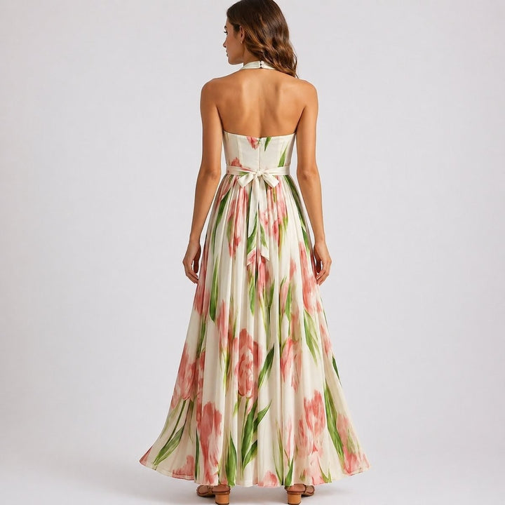 Backless halter maxi dress showing tie-waist bow and flowing floral skirt