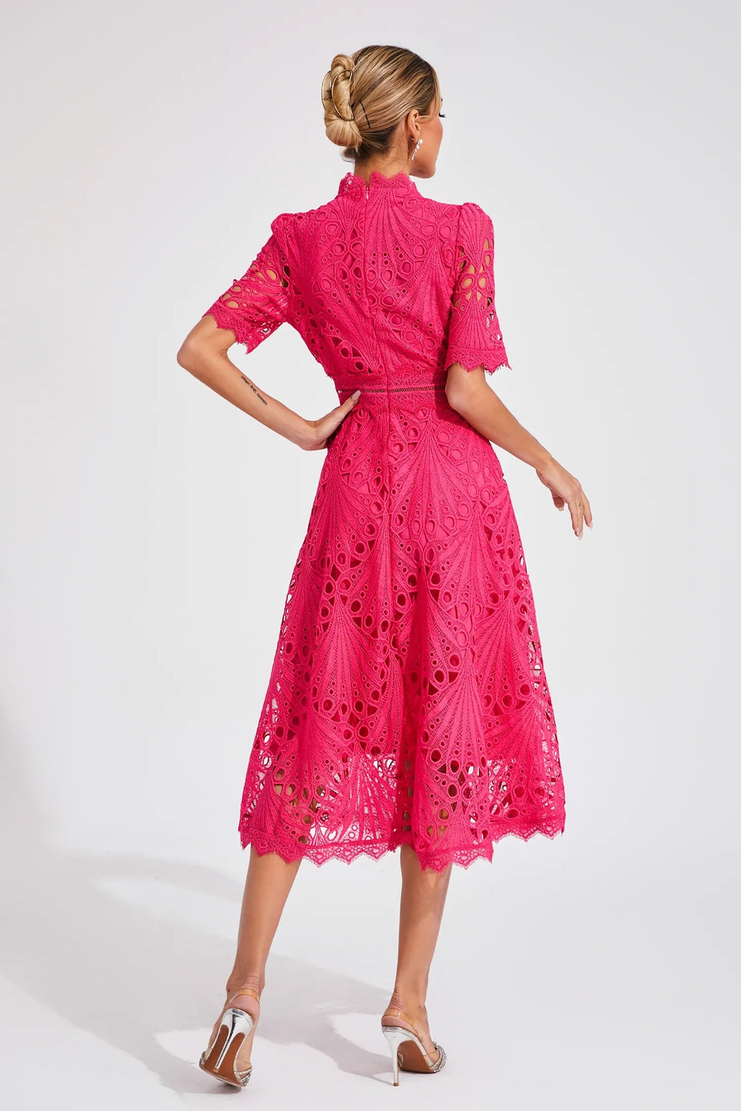 Pink lace midi dress viewed from behind showing scalloped skirt hem