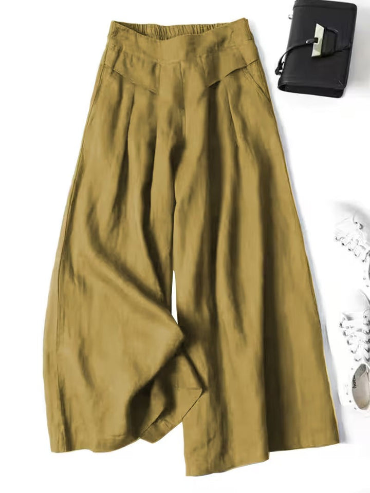 Mustard yellow wide-leg trousers with pleated waistband and flowing silhouette