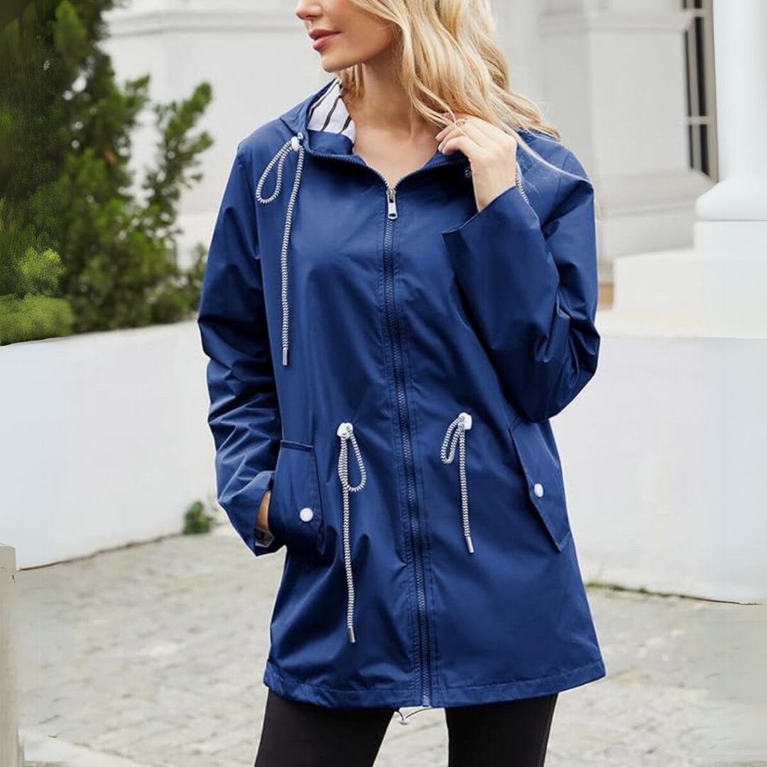 Woman wearing navy waterproof jacket with hood pulled back outdoors