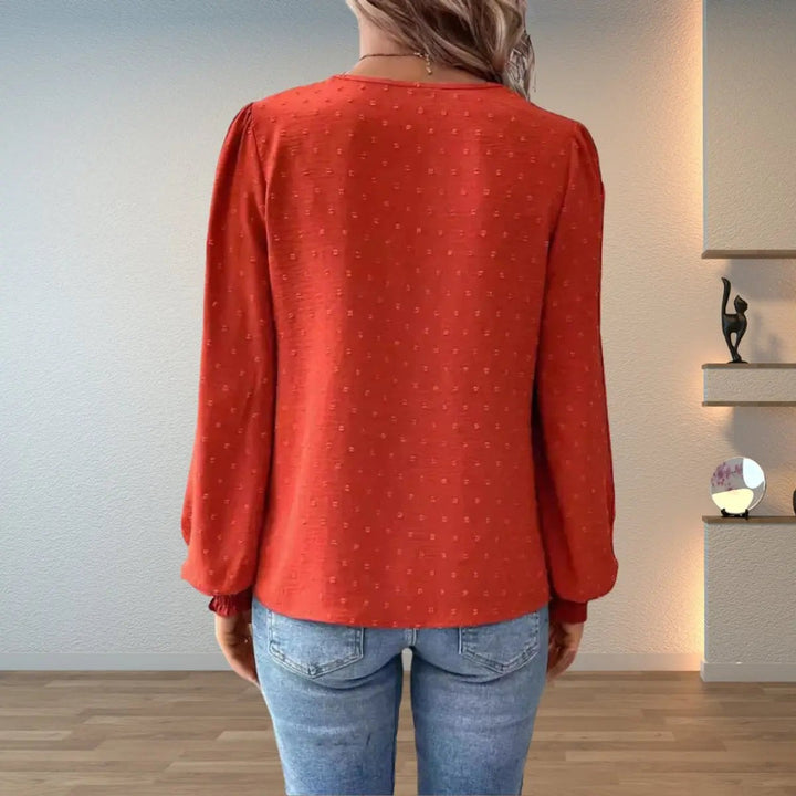 Rear view of rust orange blouse showing dotted texture and puff sleeves