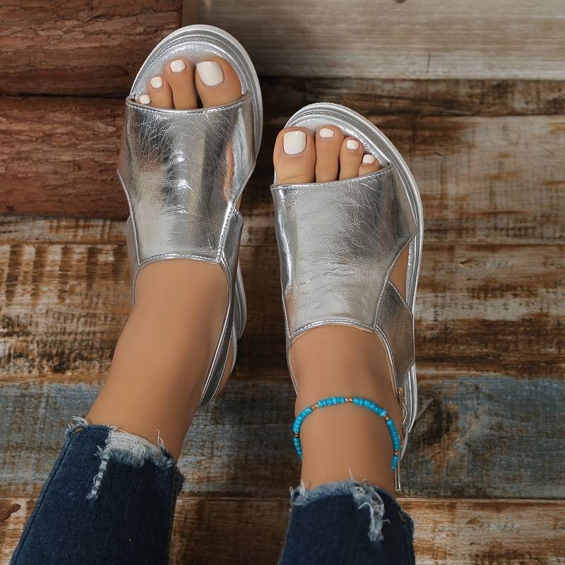 Overhead view of silver wedge sandals with peep toe and woven platform base