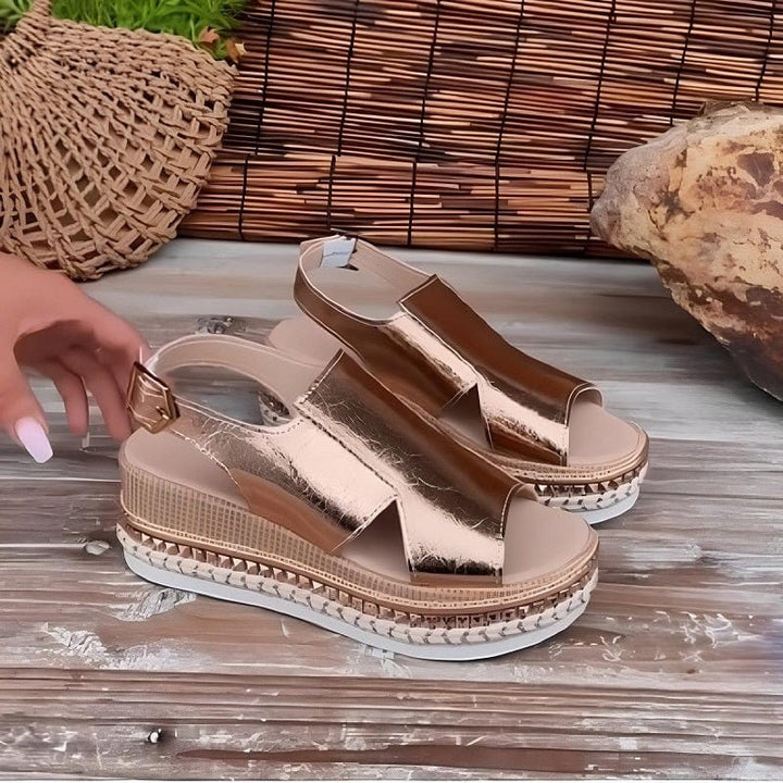 Pair of rose gold wedge sandals with buckle strap and studded platform sole